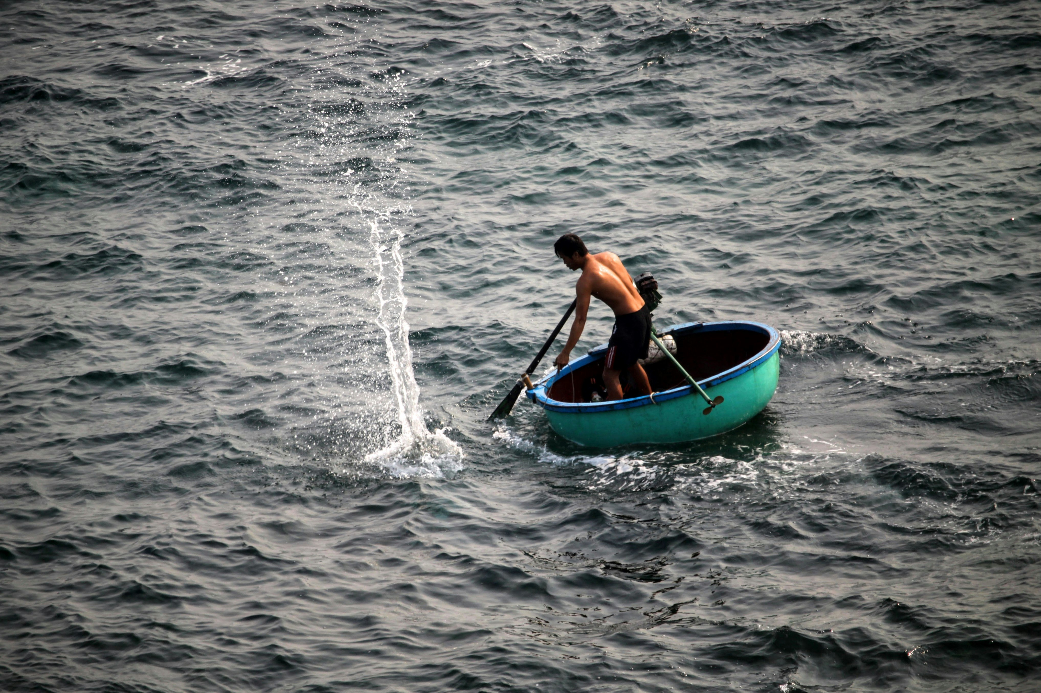 man riding on round green boat at daytime